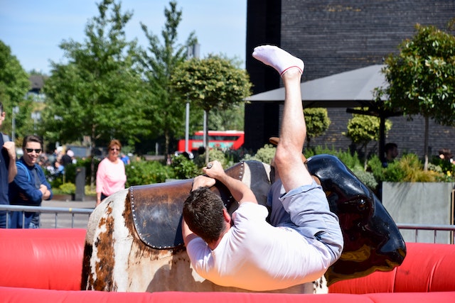 White man falling off an automated bucking bison. Photo by Isaw Company via Pexels.